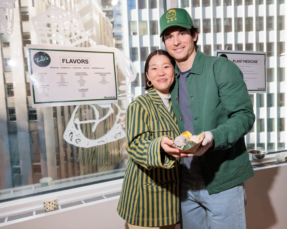 A photo of Laz and his wife. They're both smiling and hugging and both holding a tray of Laz's Ice Cream containing scoops of all the flavors.